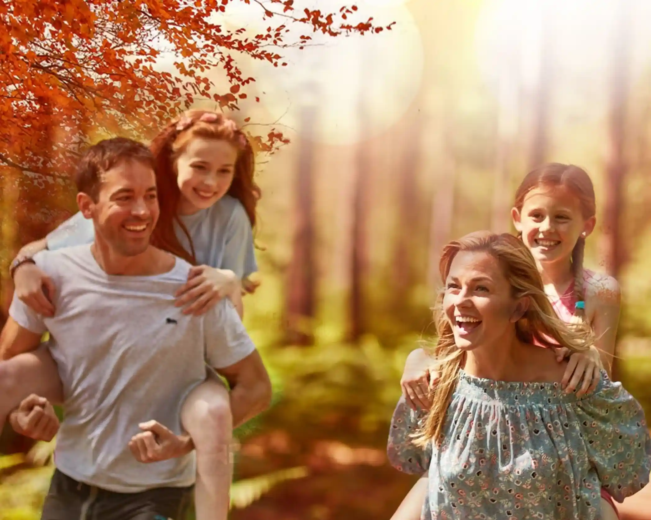A family of four, a husband and wife and two daughters are having a piggy back race in the forest. Autumn colours and happy smiling faces give a sense of holidays and happiness.