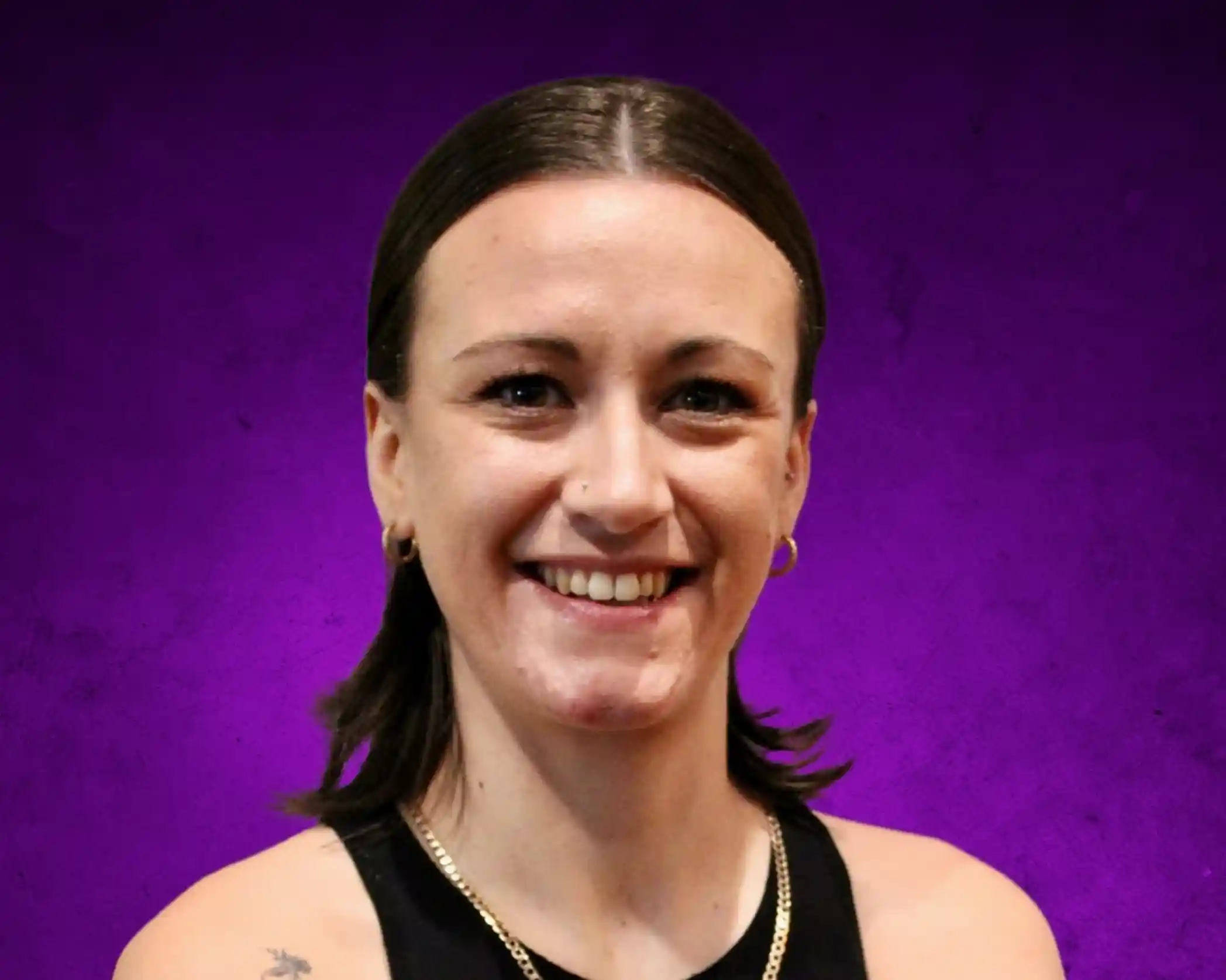A smiling woman with shoulder-length brown hair, wearing a sleeveless black top and gold hoop earrings, set against a purple background.