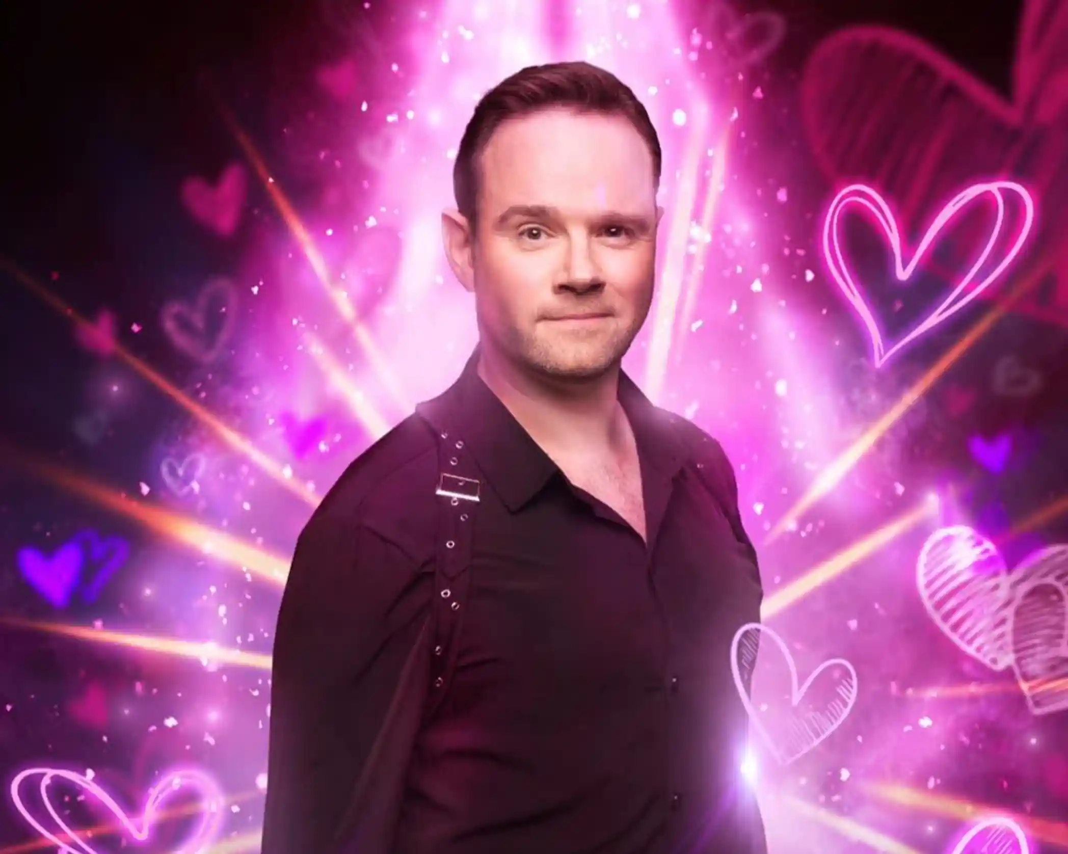 A man in a black shirt stands confidently with a sparkling pink and purple background featuring glowing hearts and light bursts.