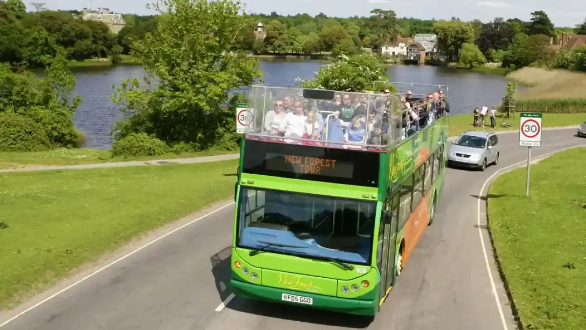 A man smiles while sitting at a table with a woman and a young boy. The boy holds a piece of food, looking playfully at the woman. Brightly colored dishes are spread across the table.