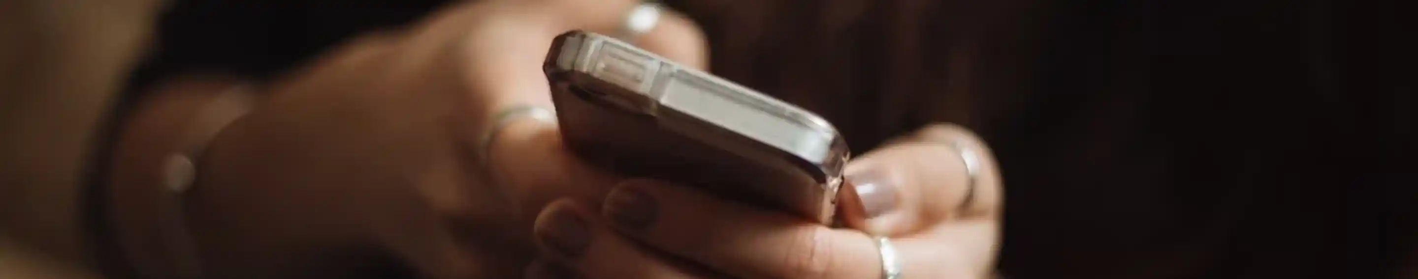 Woman's hands wearing silver jewelry and holding a mobile phone.