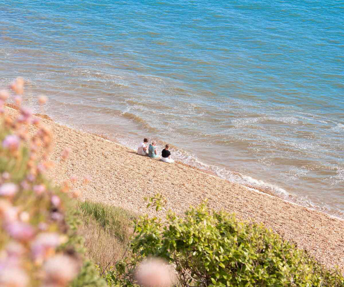 A group of animated characters from a children's show stands together, wearing colorful outfits. They are set against a backdrop of amusement park attractions, including colorful hot air balloons. The characters are smiling and appear cheerful.