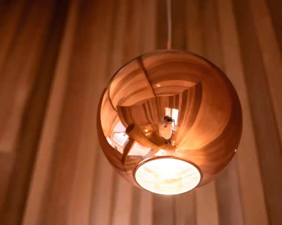 A reflective, spherical pendant light hangs from the ceiling, emanating a warm glow. The background features wooden paneling that adds a cozy ambiance.
