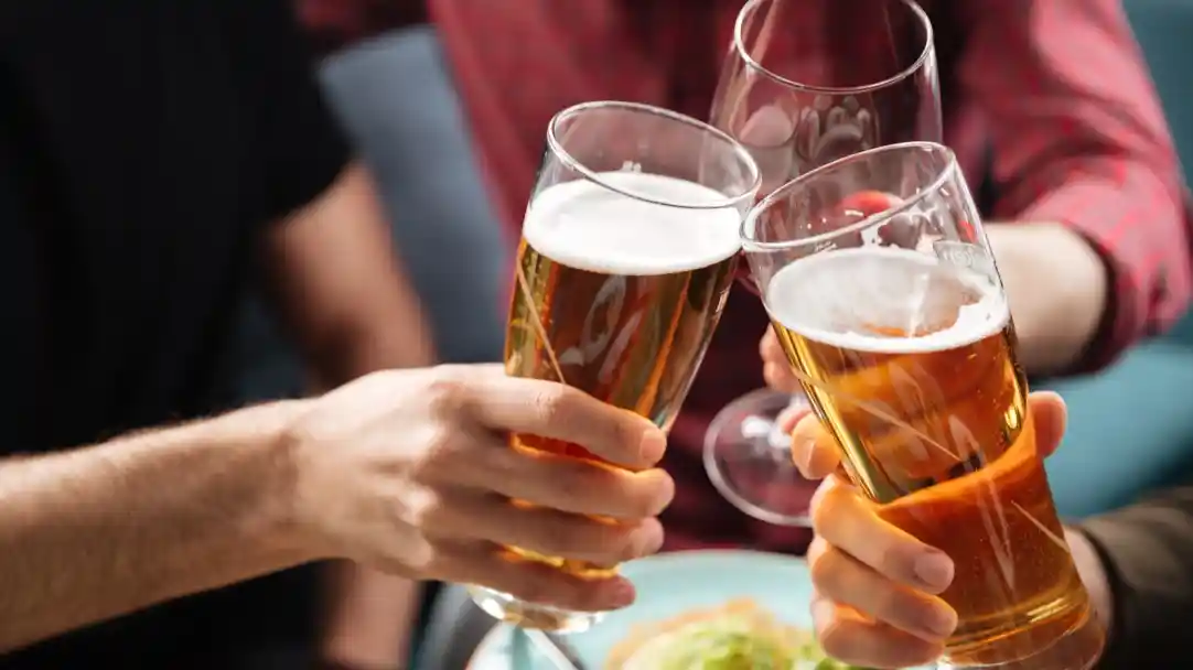 Glasses of beer clinking together in a toast, with a meal of salad in the foreground.
