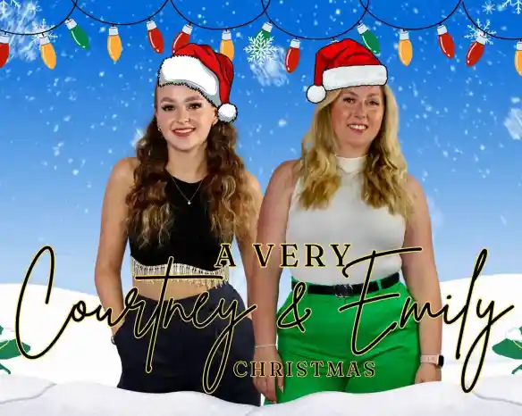 Two women stand side by side, both wearing festive red Santa hats. The background features a snowy scene with snowflakes and holiday lights. The text at the bottom reads "A Very Courtney & Emily Christmas."