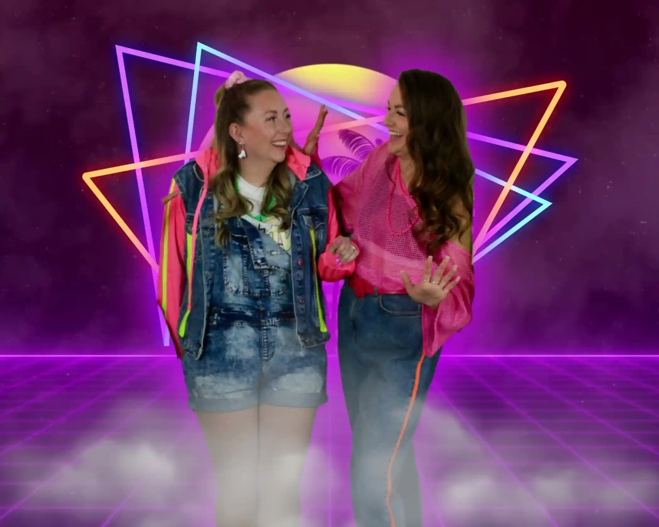 Two women in vibrant 80s-inspired outfits smile and engage playfully against a colorful, retro-themed background with neon geometric shapes and a glowing horizon.