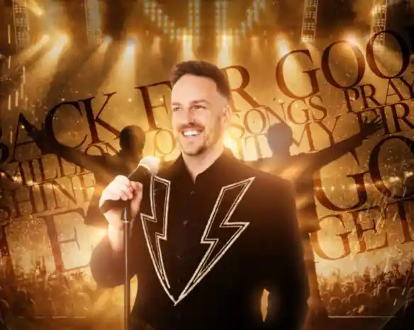 A smiling performer in a flashy jacket stands with a microphone on stage, illuminated by bright lights. The background features the words "Back for Good" and "songs," creating an energetic atmosphere.