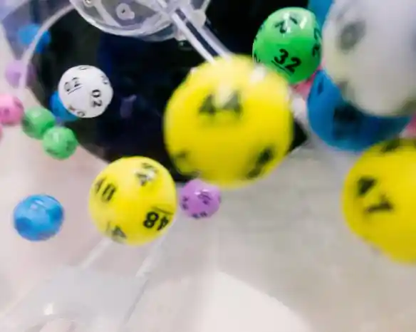Colorful lottery balls in motion, with numbers ranging from 02 to 49, captured inside a lottery drawing machine.