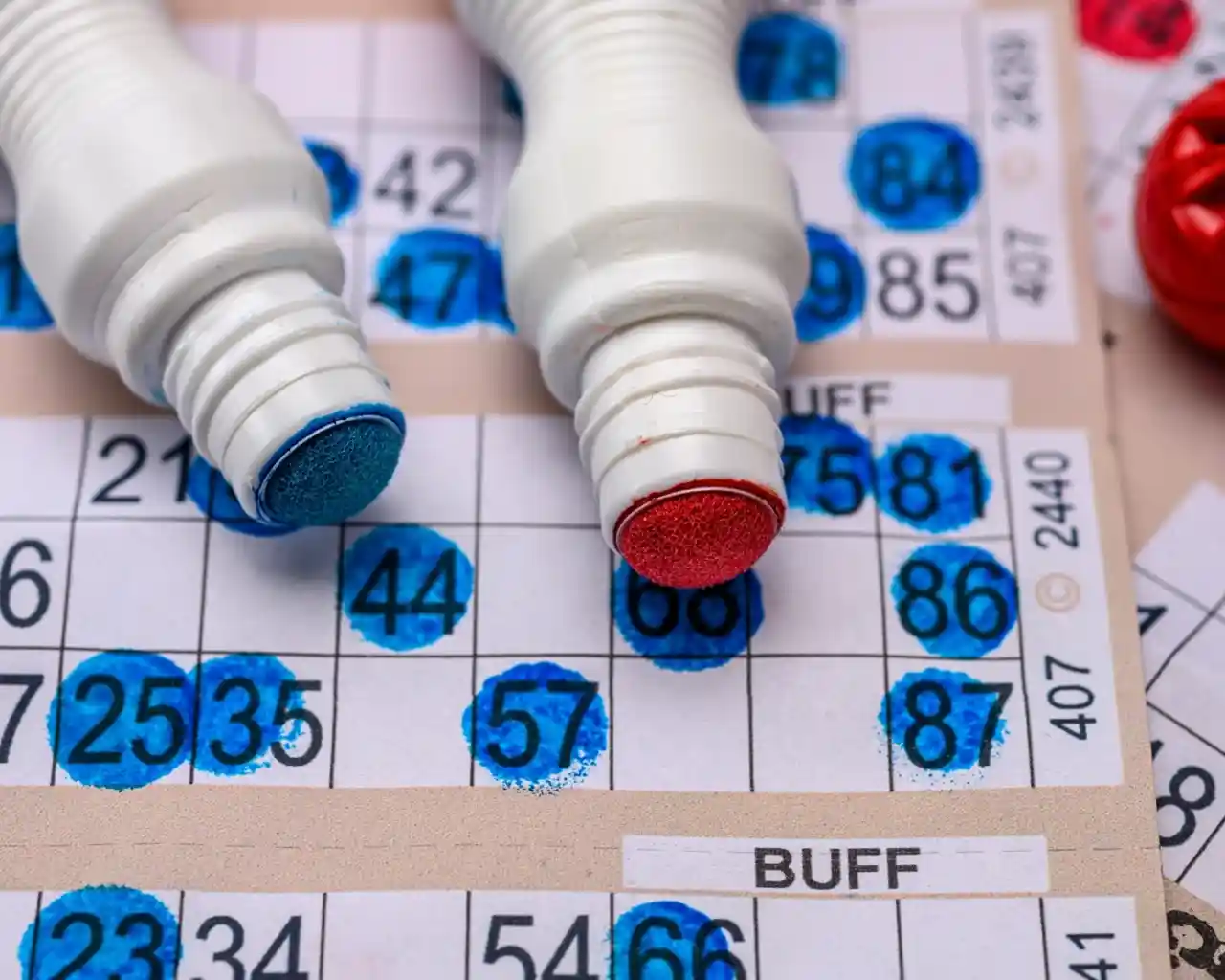 A Bingo card sheet with red and blue bingo dabber pens.