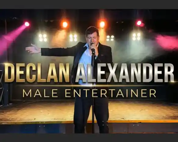A male performer stands on stage, microphone in hand, wearing a black suit and white shirt. Colorful stage lights illuminate the background, creating a vibrant atmosphere. The text "Declan Alexander Male Entertainer" is prominently displayed.