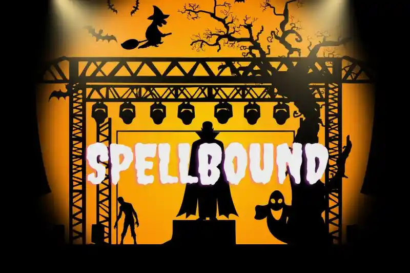 A spooky stage scene with an orange background, featuring silhouettes of a witch on a broom, a ghost, a tree with bats, and a zombie. The word "SPELLBOUND" is prominently displayed in large, whimsical letters.