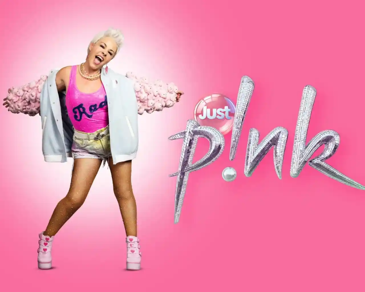 A person with short blonde hair is posing energetically in a pink-themed outfit, featuring a bright pink tank top and a light blue jacket with fluffy pink accents. They have a playful expression and are wearing pink high-top sneakers, set against a vibrant pink background with the stylized text "Just p!nk."