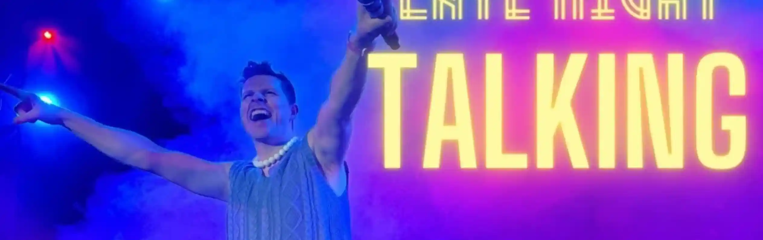 A performer with a joyful expression stands on stage, holding a microphone and wearing a sleeveless sweater and embellished jeans. Colorful lights and smoke create a vibrant atmosphere, with "Late Night Talking" prominently displayed in bold text.