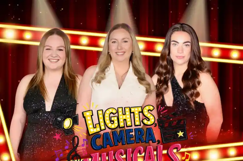 Three smiling women stand against a vibrant backdrop featuring stage lights and musical notes. The text "Lights, Camera, Musicals!" is prominently displayed in colorful letters. The women are wearing sparkly outfits and the setting suggests a theatrical theme.