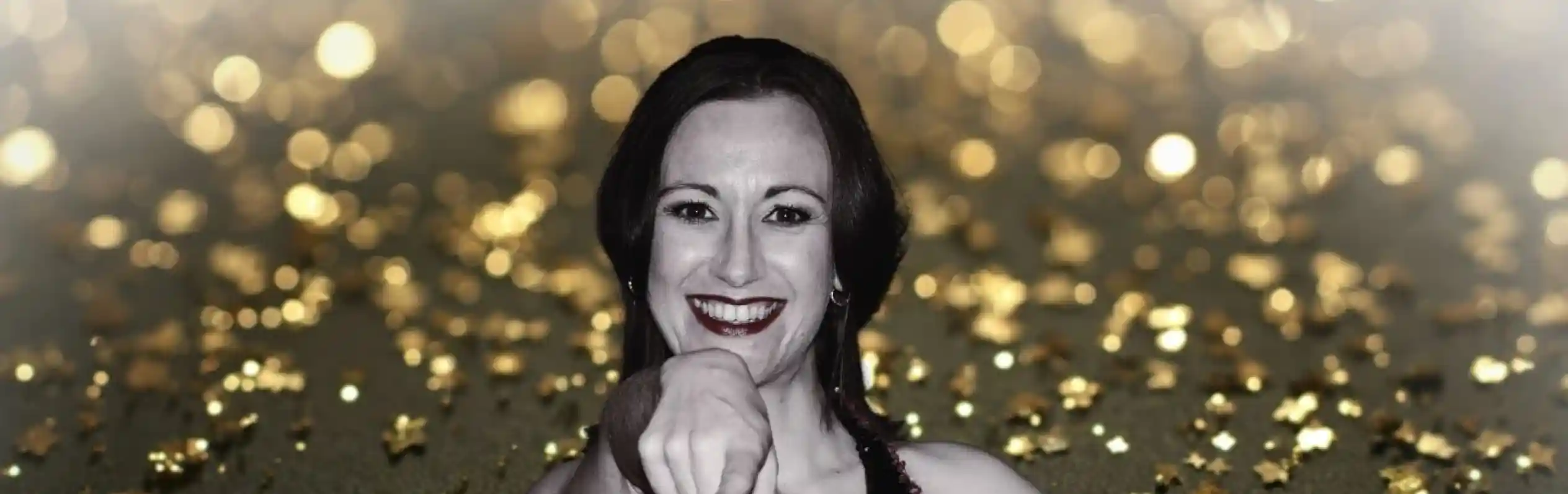 A woman in a sequined dress with bold stripes poses confidently, pointing playfully at the camera. The background features a shimmering golden sparkle effect.