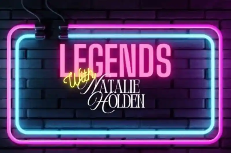 A neon sign displaying the words "Legends" in bold pink letters, with "With Natalie Holden" written in an elegant yellow script underneath, set against a dark brick background.