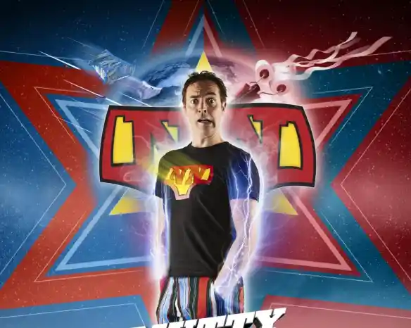 A man stands confidently in a superhero-style outfit with a colorful logo on his chest, surrounded by vibrant star patterns. He has a surprised expression and electric energy swirls around him, adding a dynamic effect. The background features bold colors of blue and red.