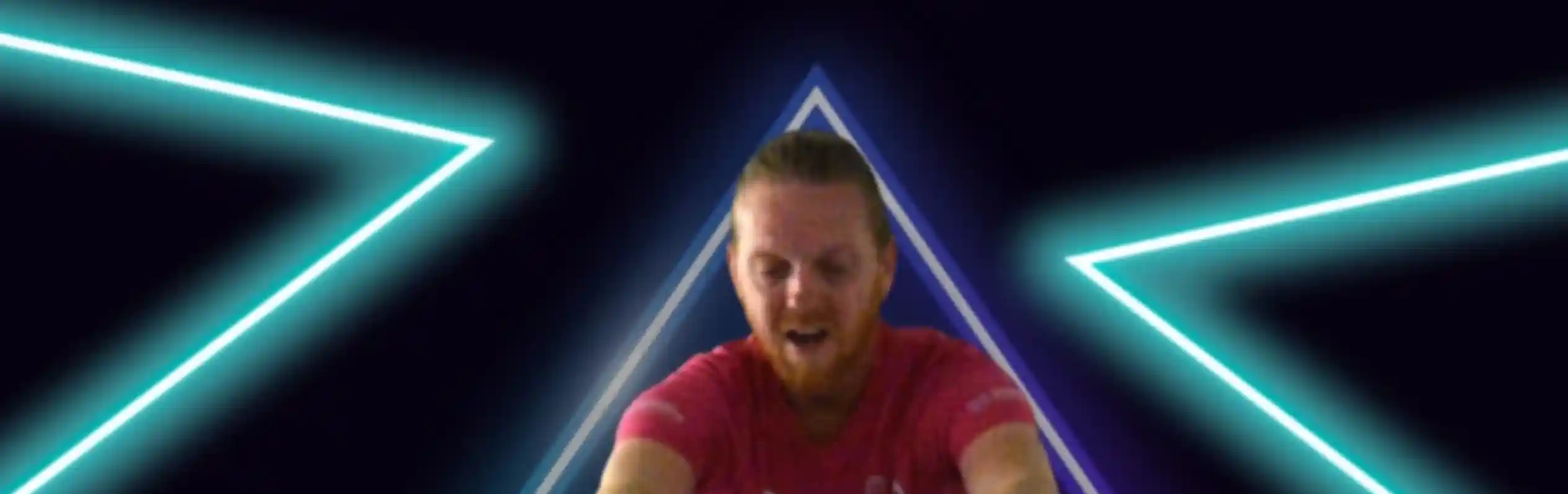 A man in a pink shirt is demonstrating a science experiment involving a clear sphere, surrounded by neon triangular shapes and bright lighting. The text above reads "The Science Dude Presents" and below, "The curious world of."