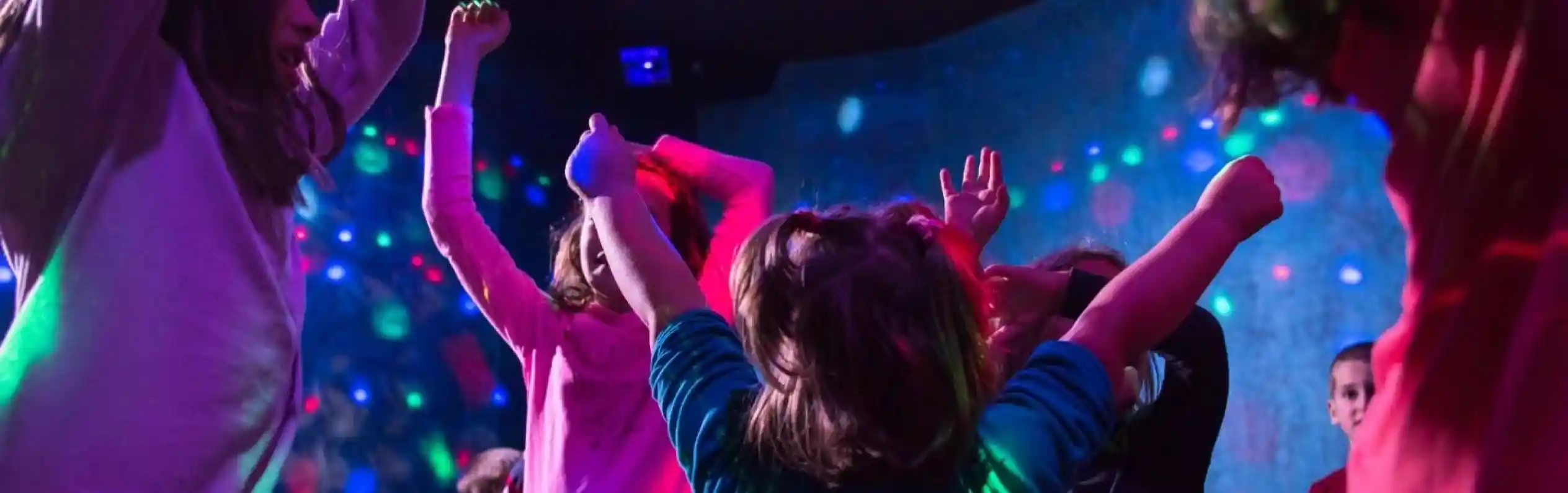 Children dancing and celebrating in a vibrant, colorful environment with disco lights and a joyful atmosphere.