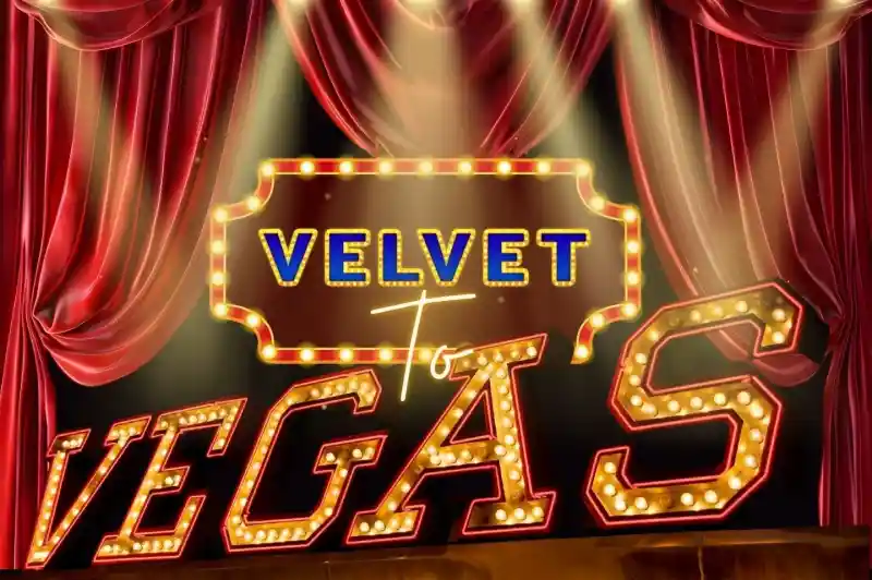 A bright marquee sign reading "Velvet to Vegas" illuminated by lights, set against a backdrop of rich red curtains. Spotlights shine on the sign, creating a vibrant theatrical atmosphere.
