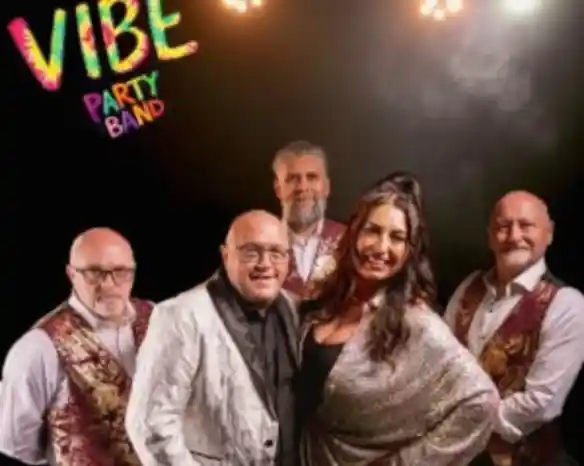 A party band poses together, featuring five members in stylish outfits. The front includes a woman in a sparkling top and a man in a sequined jacket, while the others wear vests. Colorful text in the corner reads "VIBE PARTY BAND." Bright stage lights create a festive atmosphere.