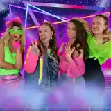 Four women wearing vibrant 80s-inspired outfits pose against a colorful retro-themed background. They are making playful poses, showcasing bright accessories like neon sunglasses and hairbands.