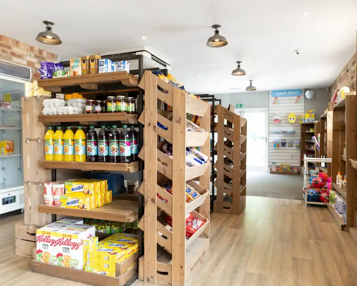 Shelves stacked with a variety of snacks, drinks, and toys, arranged in a bright store interior. Wood accents and modern lighting create a welcoming atmosphere.