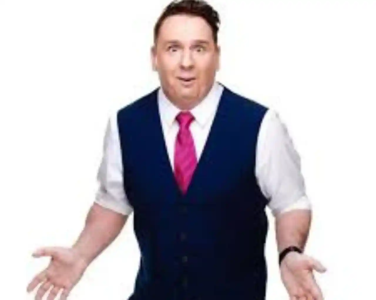 A man in a blue vest and white shirt with a pink tie stands with an expressive face, hands raised and open, conveying surprise or confusion.