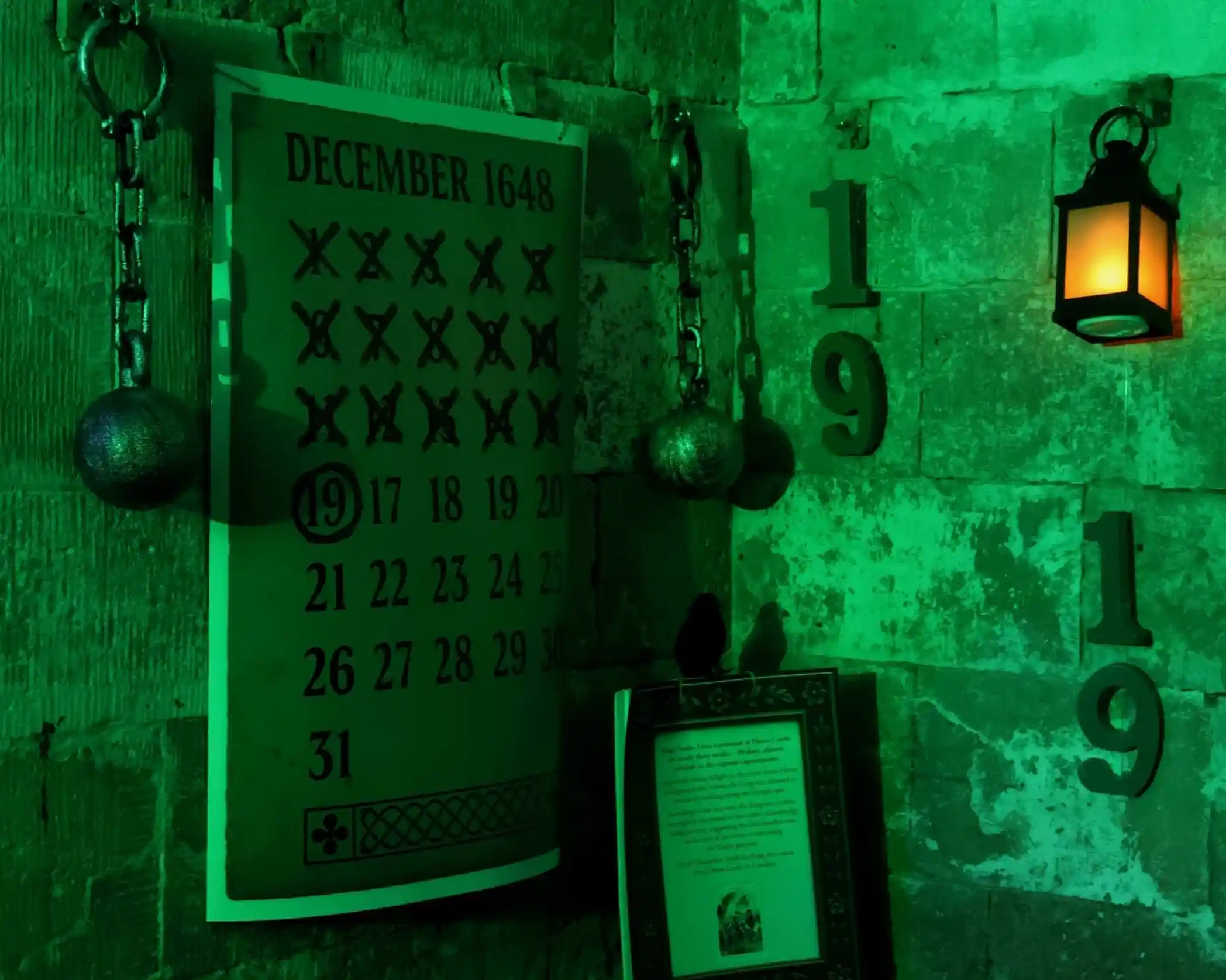 A green-lit wall features a calendar for December 1648 with many crossed-out dates, two decorative chains with metallic balls, and a lantern casting a warm glow. The numbers "19" are visible on the wall.