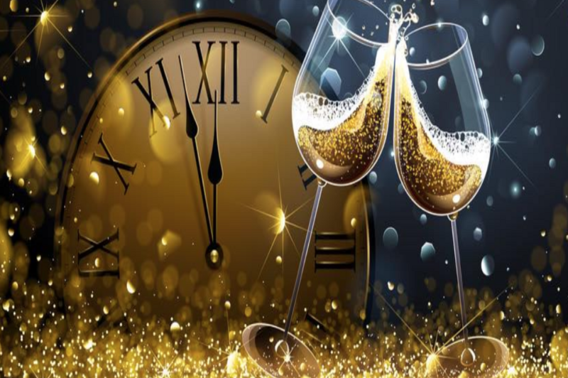 Two champagne glasses clink together in celebration, with bubbles rising in the sparkling liquid. In the background, a large clock shows the time approaching midnight, surrounded by golden glitter and festive lights.