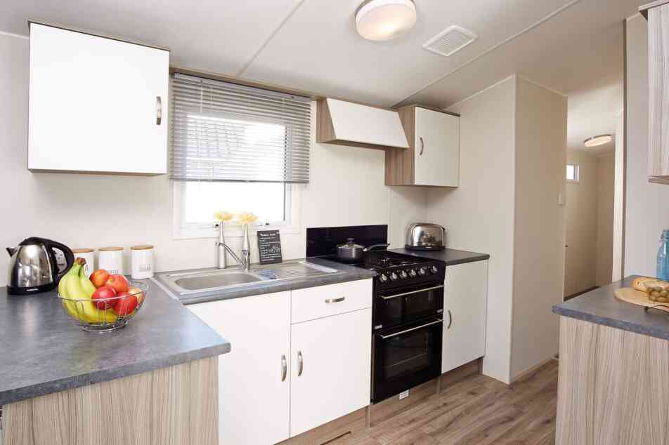 A modern kitchen displaying a stove, sink, and refrigerator, illustrating a practical area for cooking and cleaning.