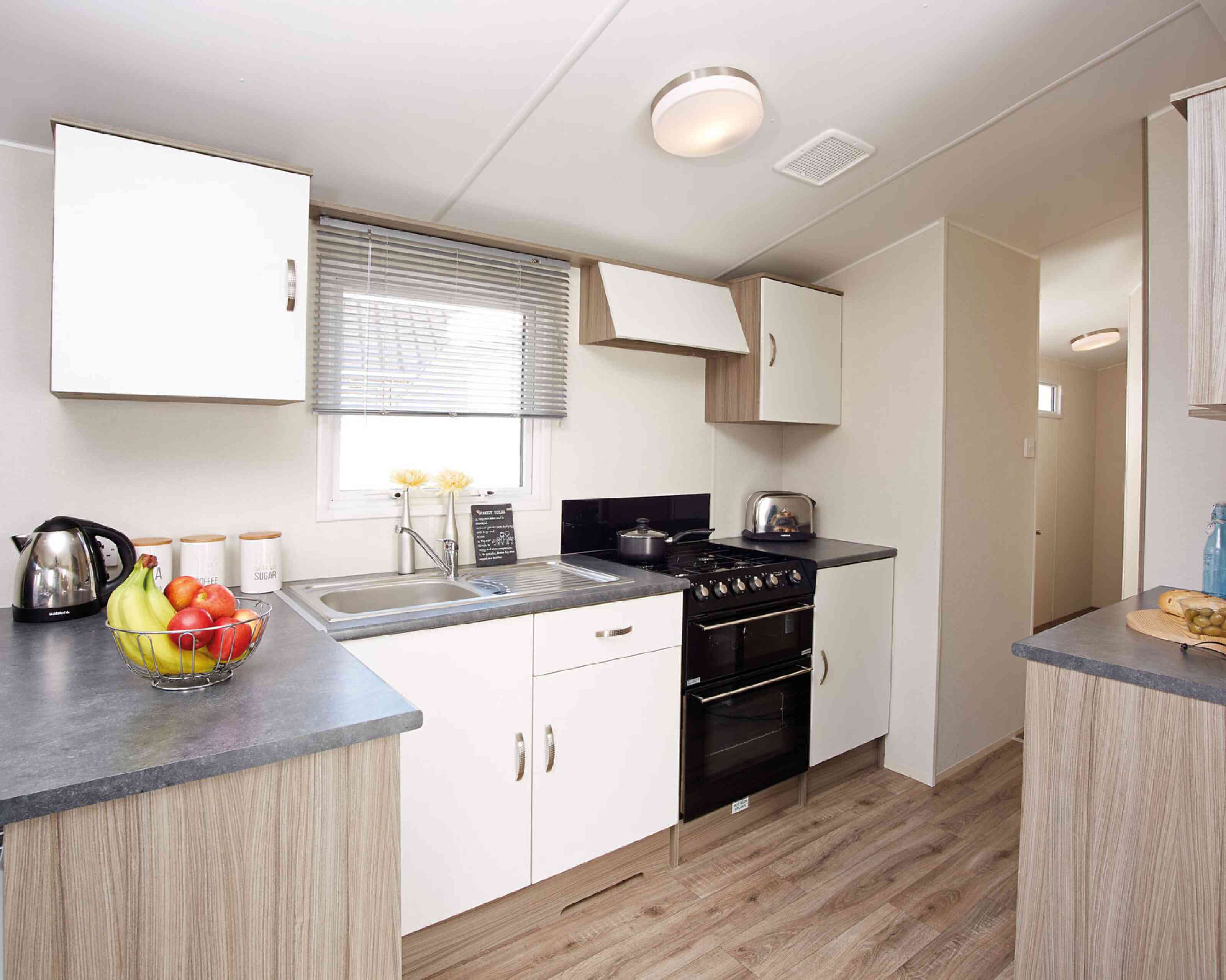 A modern kitchen displaying a stove, sink, and refrigerator, illustrating a practical area for cooking and cleaning.