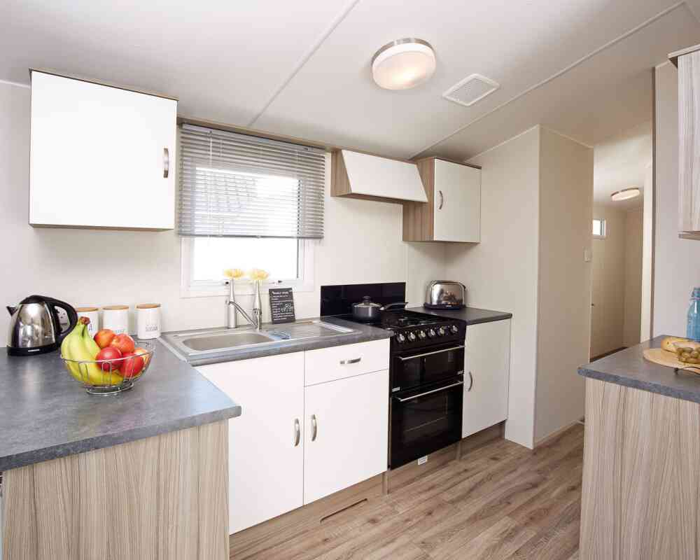 A modern kitchen displaying a stove, sink, and refrigerator, illustrating a practical area for cooking and cleaning.