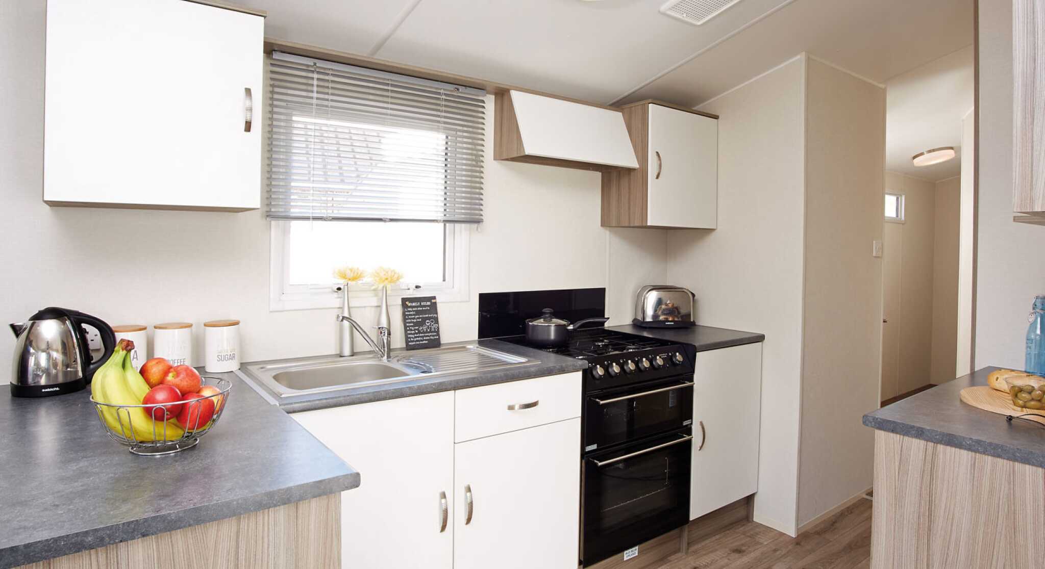 A modern kitchen displaying a stove, sink, and refrigerator, illustrating a practical area for cooking and cleaning.