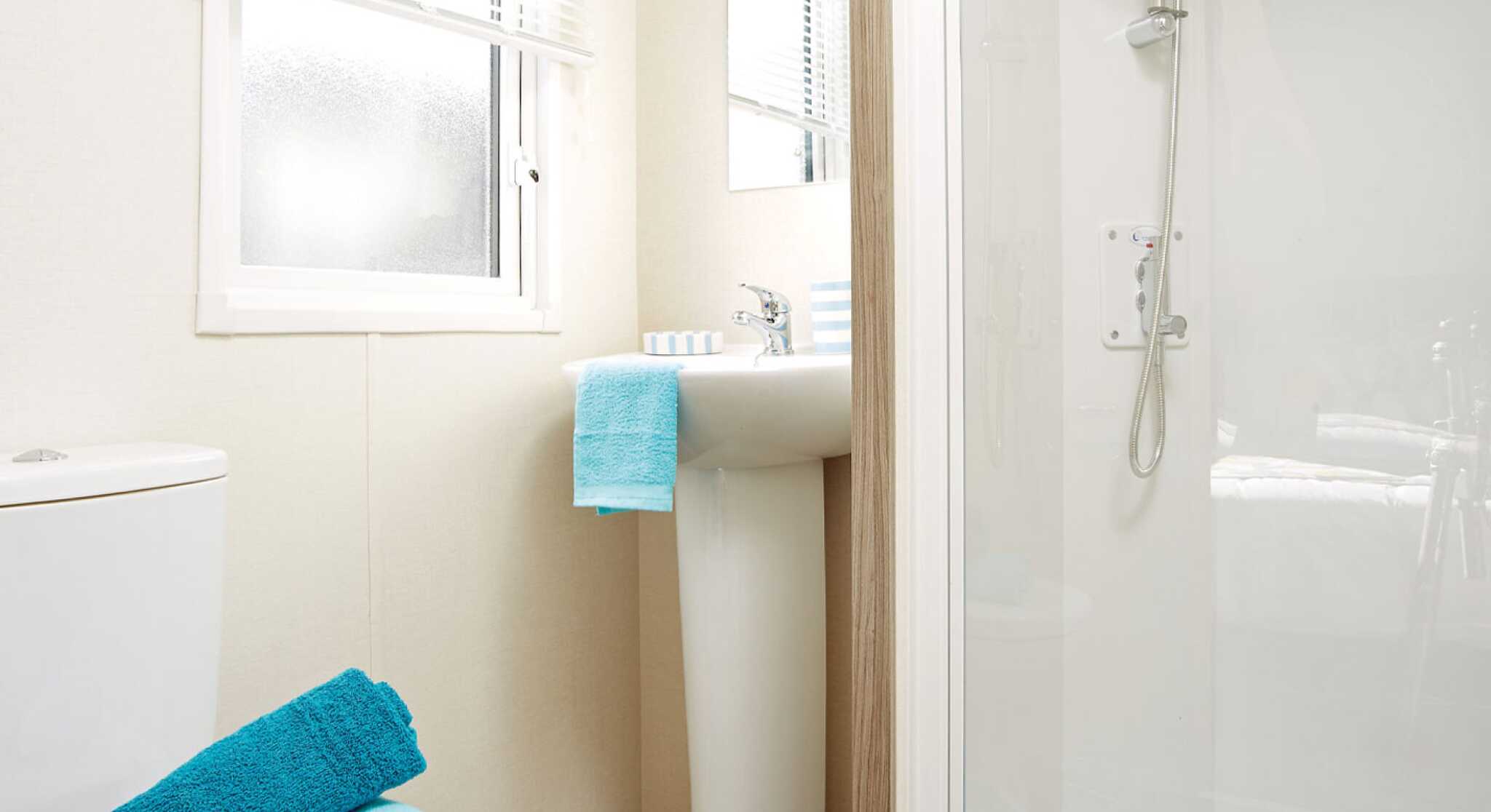 A well-organized bathroom containing a toilet, sink, and shower, with contemporary fixtures and a soothing colour palette.