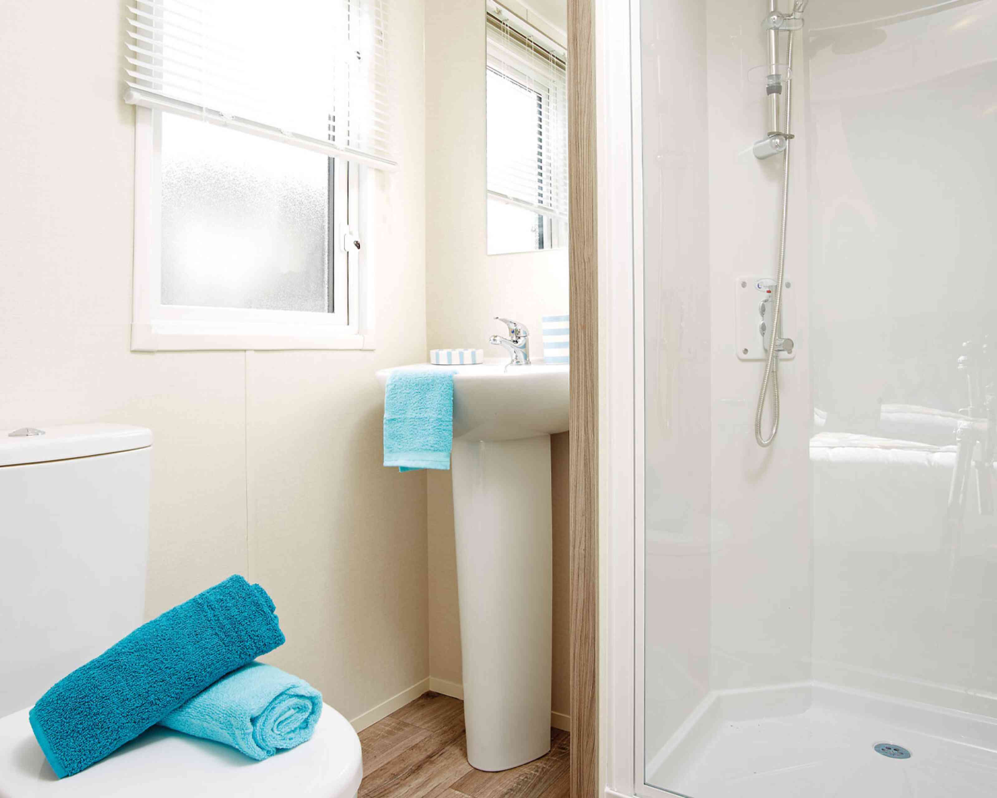 A well-organized bathroom containing a toilet, sink, and shower, with contemporary fixtures and a soothing colour palette.