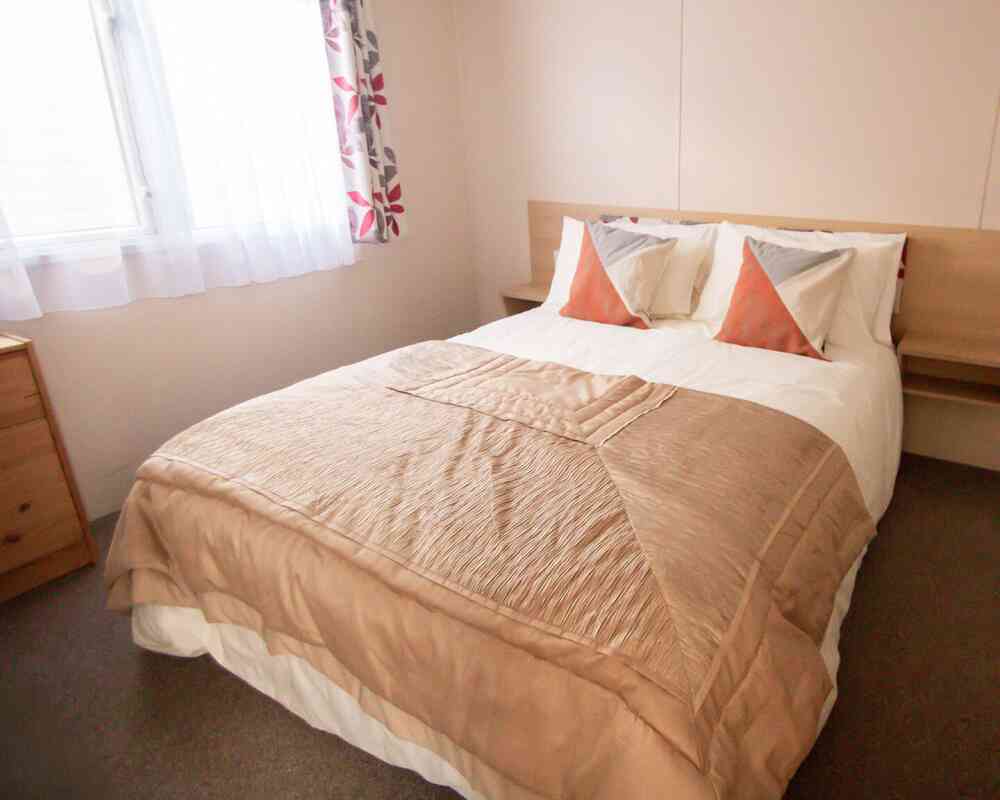 A neatly made bed featuring a soft white blanket draped over the top.