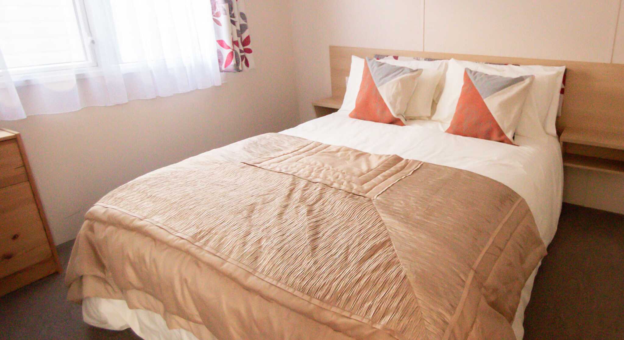 A neatly made bed featuring a soft white blanket draped over the top.