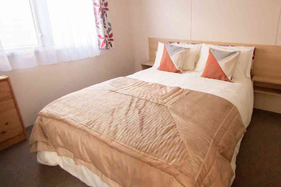 A neatly made bed featuring a soft white blanket draped over the top.