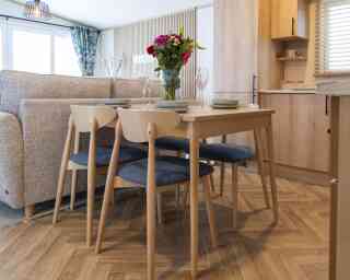 A cosy kitchen and dining area inside a mobile home, featuring modern appliances and a small dining table.