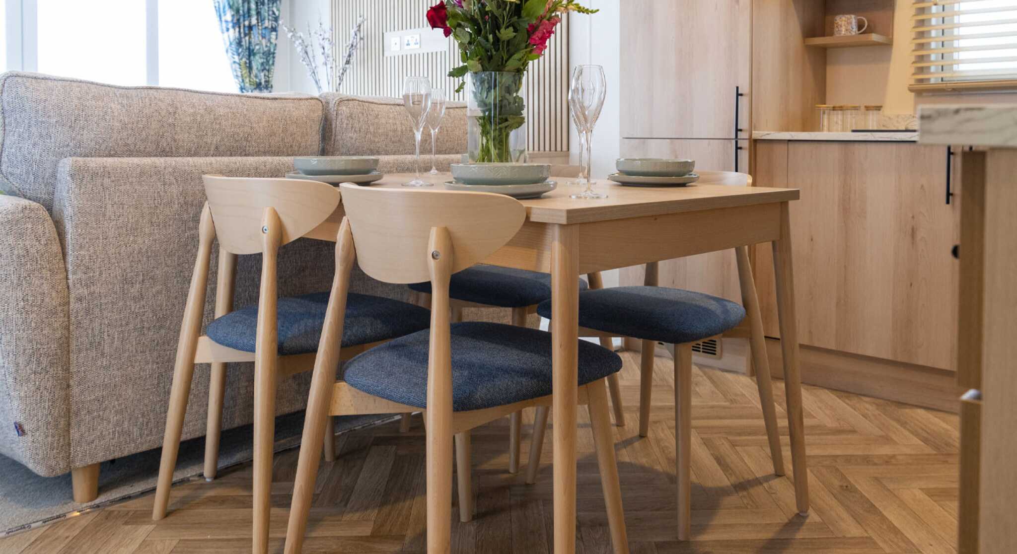 A cosy kitchen and dining area inside a mobile home, featuring modern appliances and a small dining table.