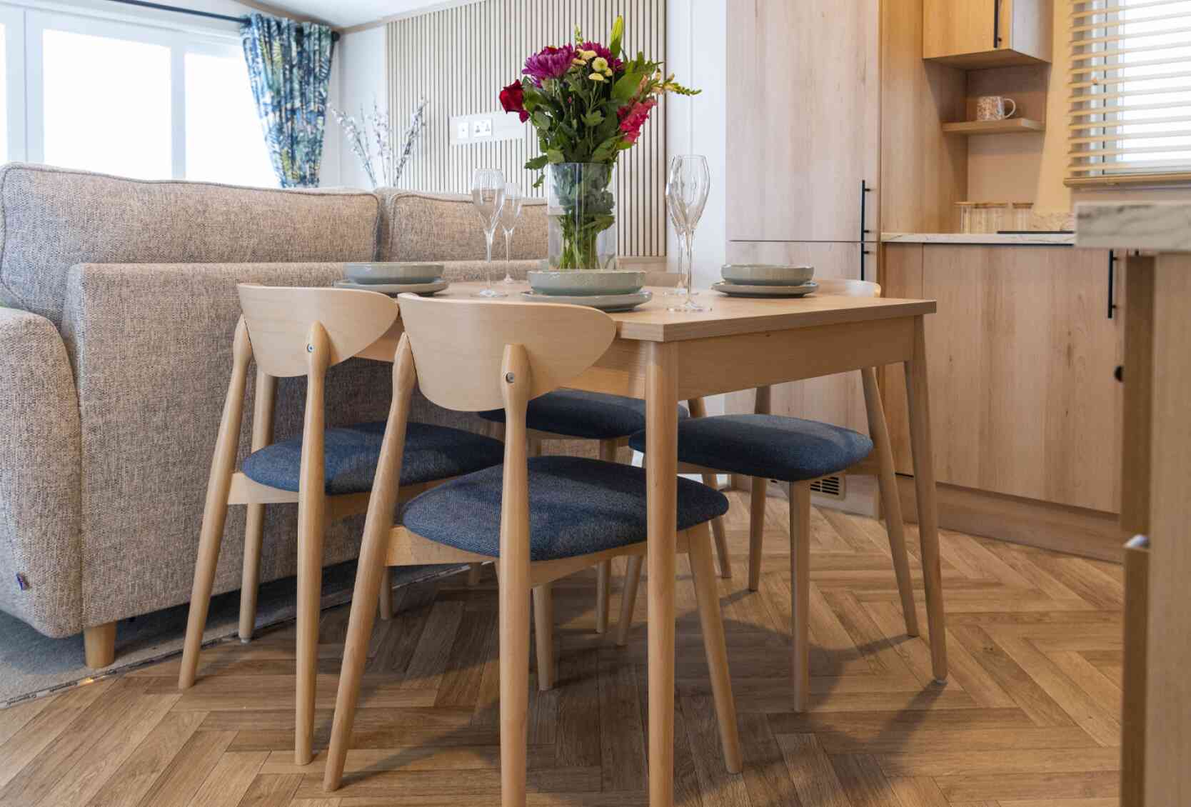 A cosy kitchen and dining area inside a mobile home, featuring modern appliances and a small dining table.