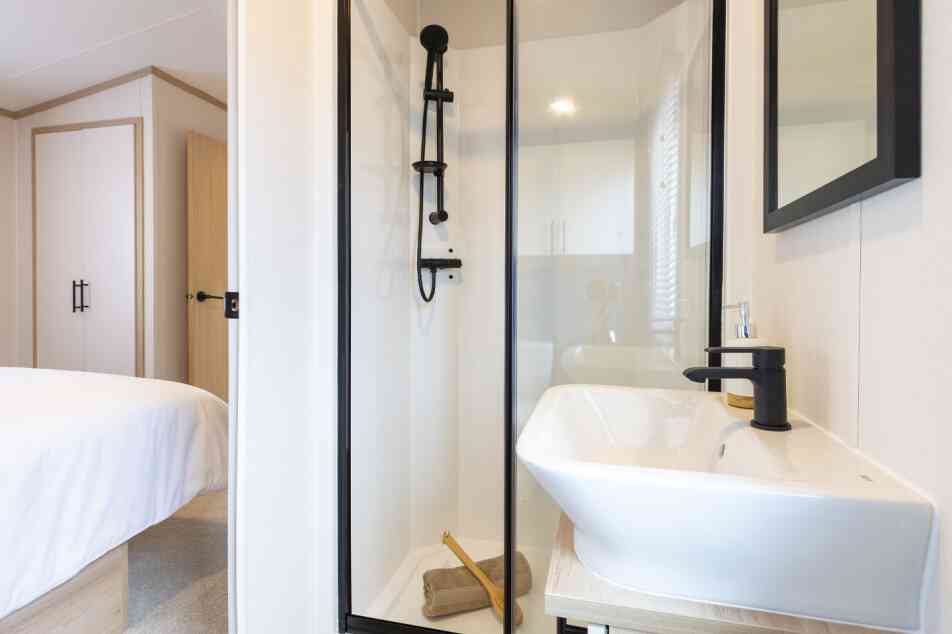A well-lit bathroom with a stylish shower and a minimalist sink, designed with neutral tones and elegant finishes.