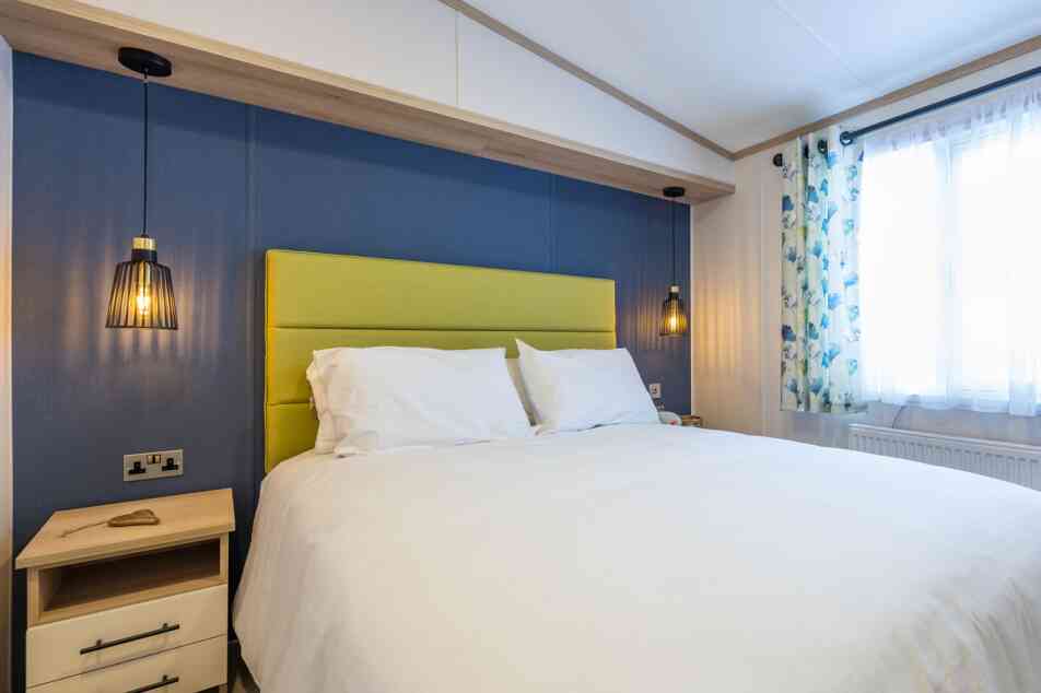 A stylish bedroom showcasing a white bed set against vibrant blue walls.