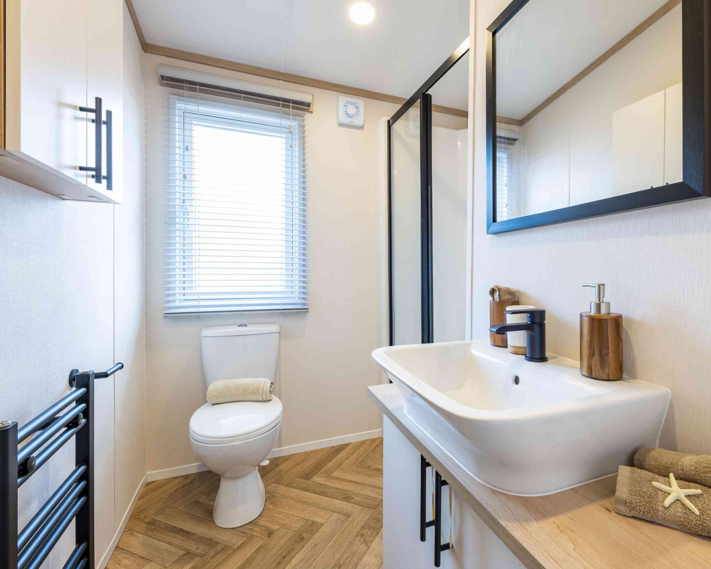 A modern bathroom layout showcasing a sink, toilet, and a mirror, all arranged neatly in a well-lit environment.