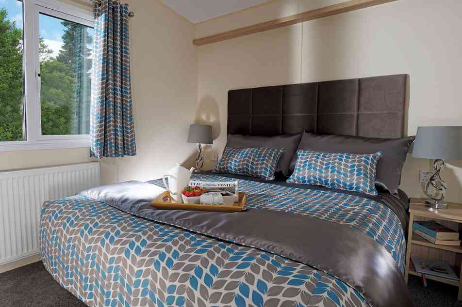 A stylish bedroom with a comfortable bed and a tray on the nightstand, adding a touch of elegance to the space.