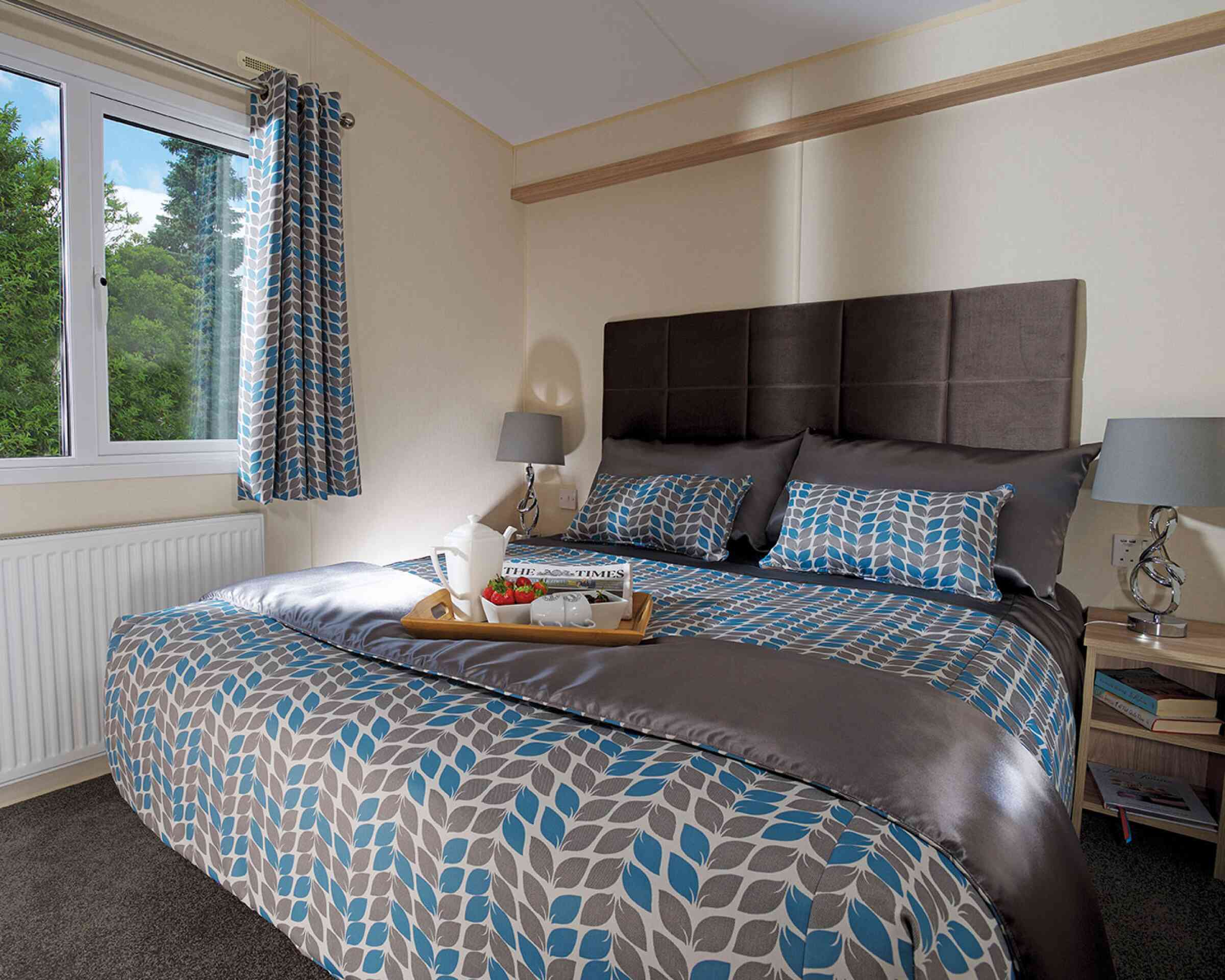 A stylish bedroom with a comfortable bed and a tray on the nightstand, adding a touch of elegance to the space.