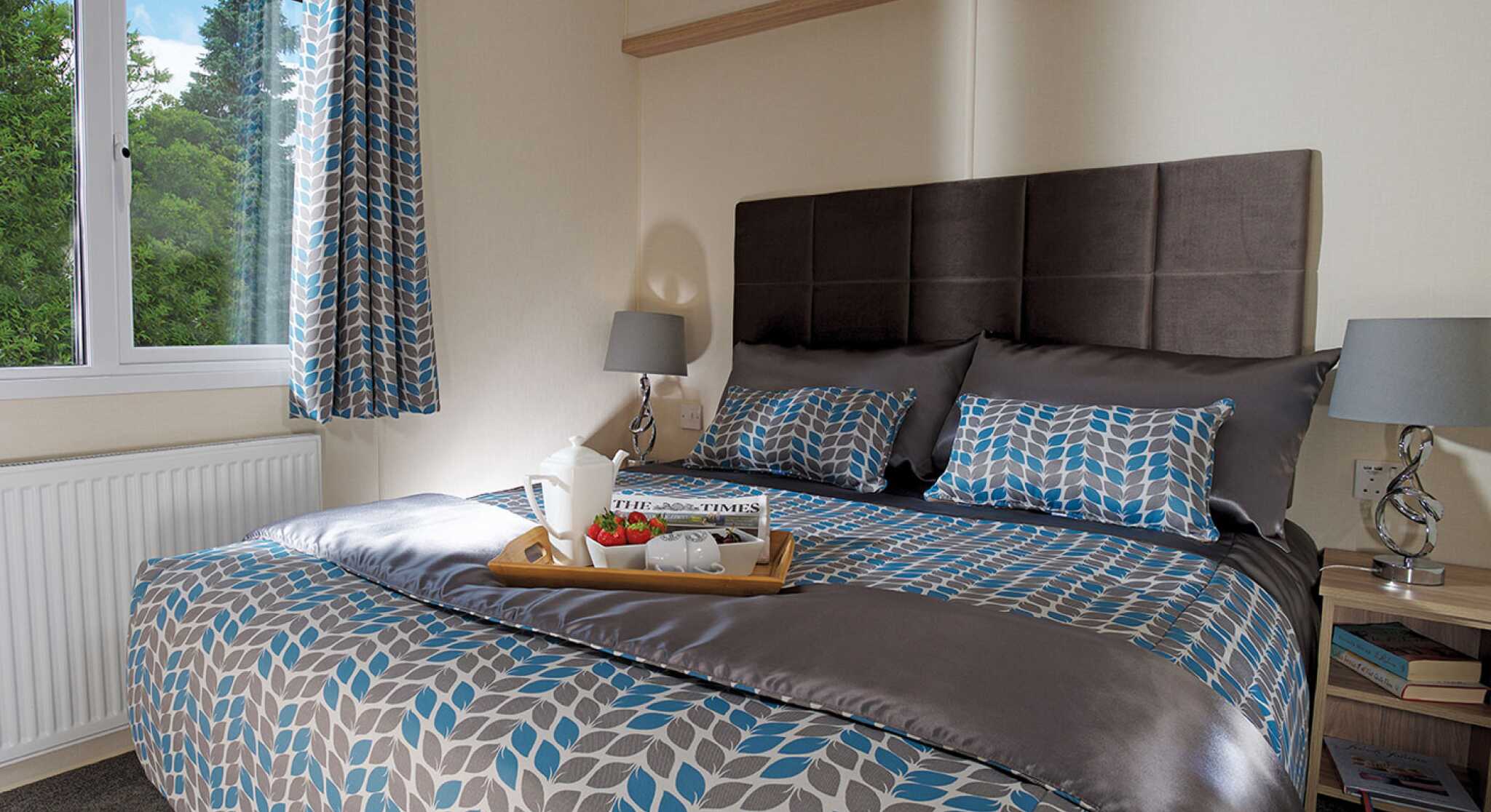 A stylish bedroom with a comfortable bed and a tray on the nightstand, adding a touch of elegance to the space.