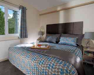 A stylish bedroom with a comfortable bed and a tray on the nightstand, adding a touch of elegance to the space.