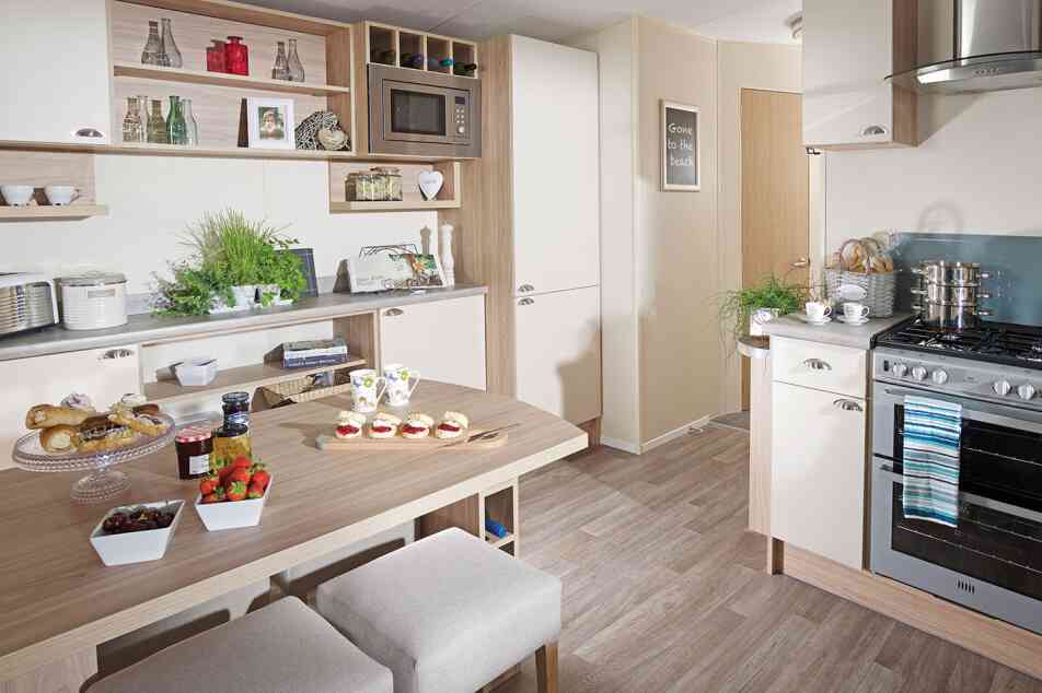 A cosy kitchen with a dining table and four chairs, showcasing cabinets and kitchenware in the surrounding area.